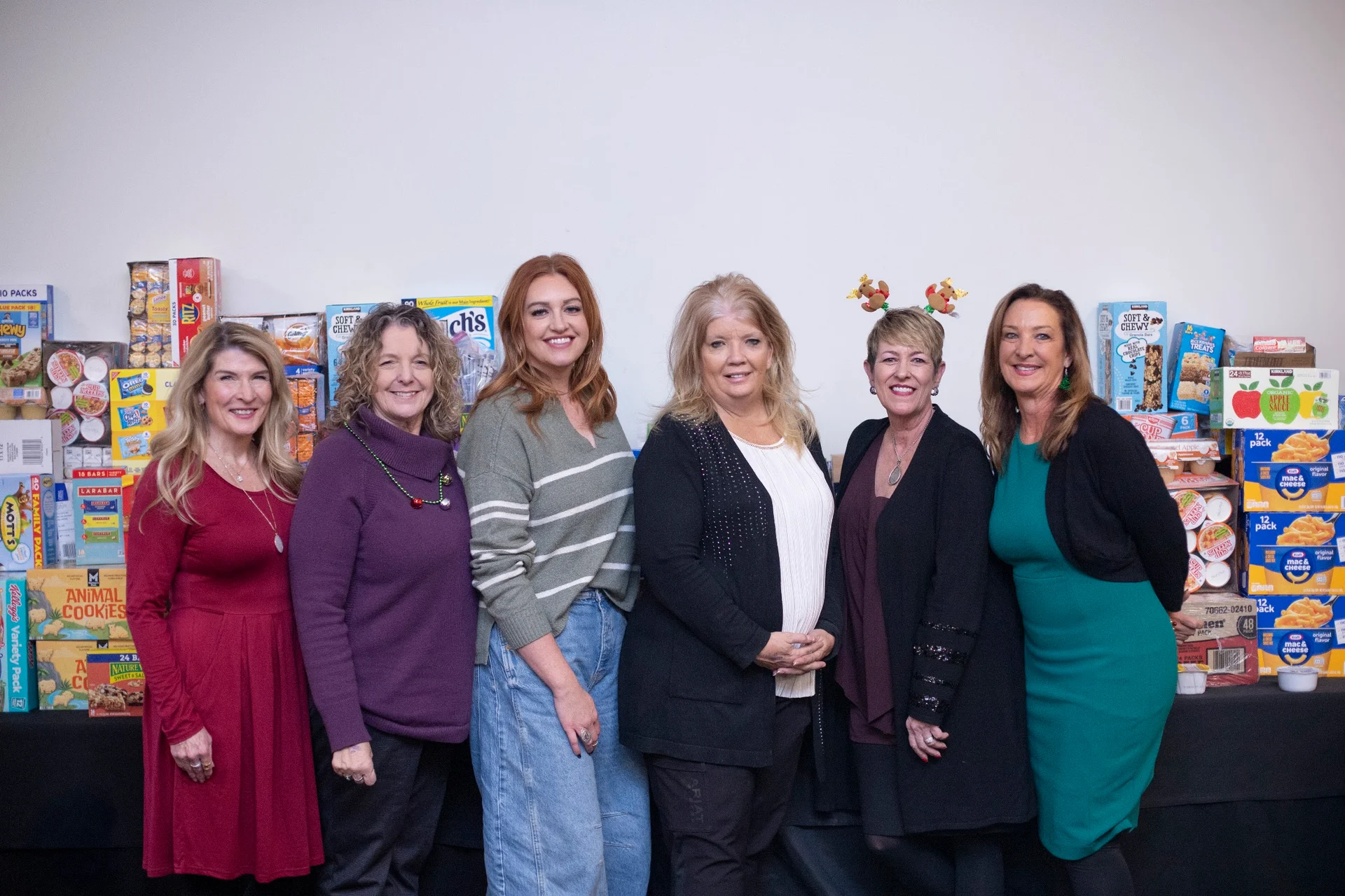 Six women smiling in front of donated food at the 2025 event