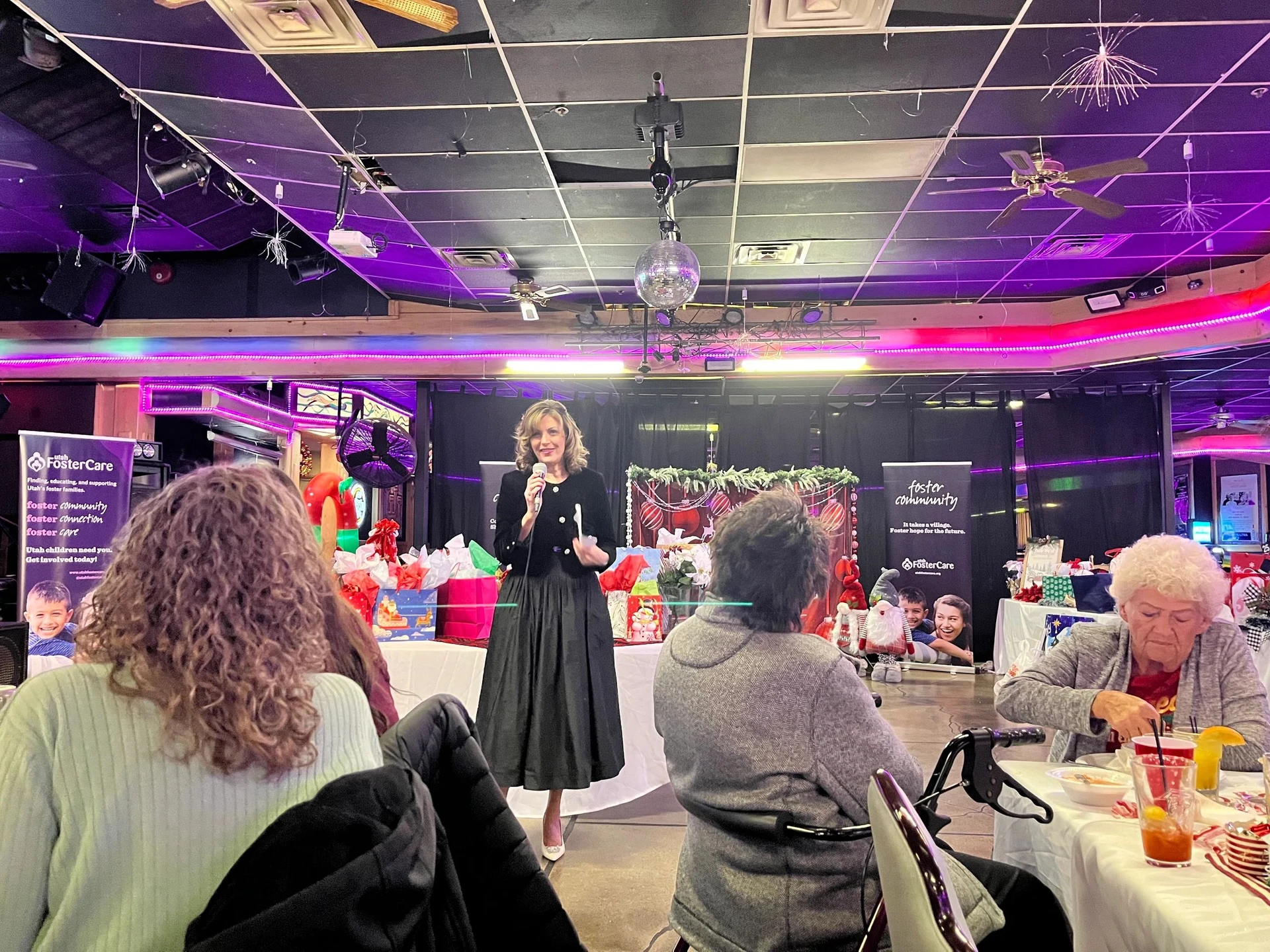 A speaker addresses Mamma Bears guests seated at decorated tables during a past Ornament Exchange gathering