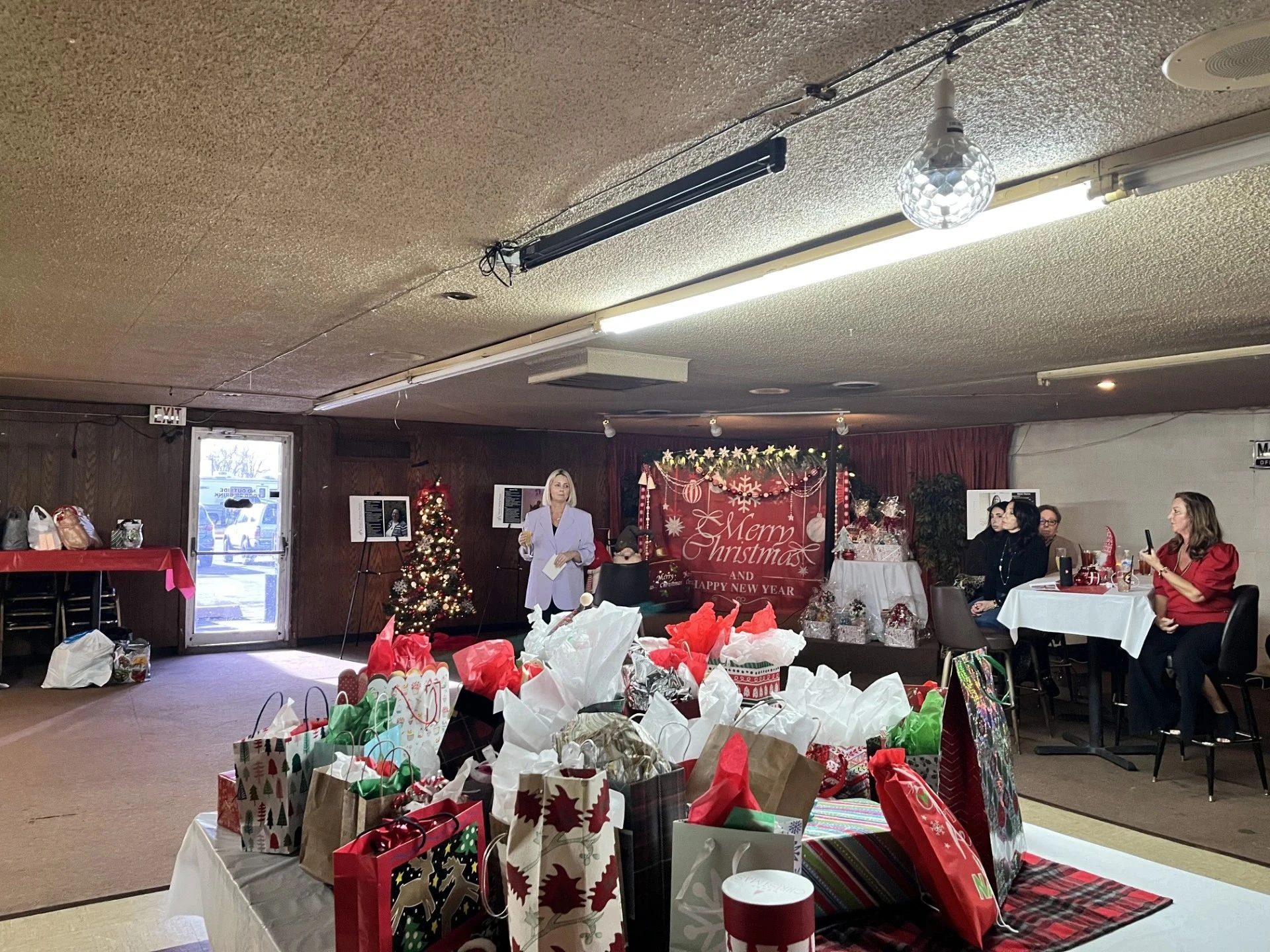 Guests and gift tables filling a decorated holiday gathering room